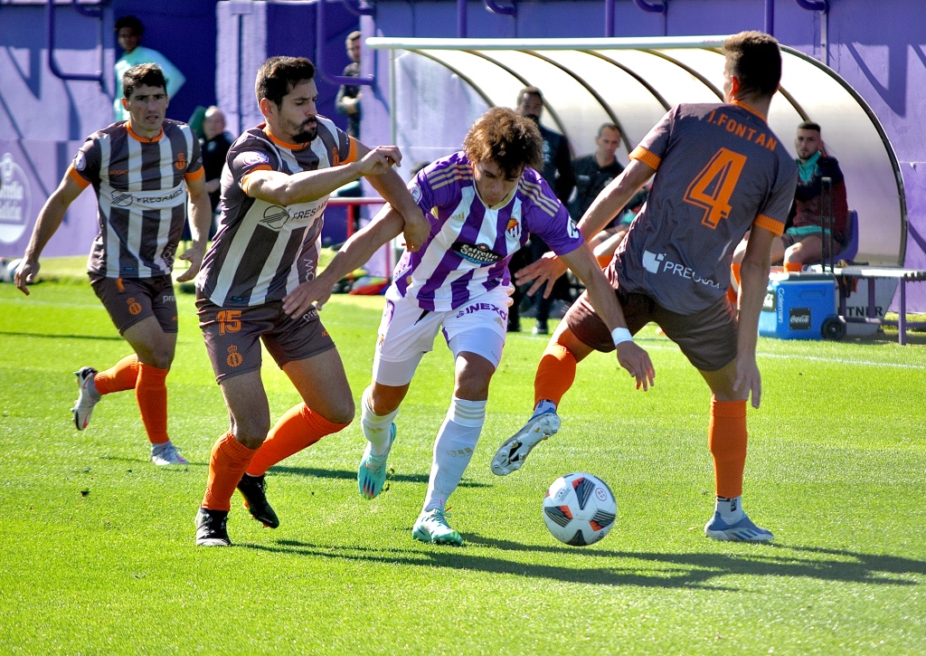 Se muestra a Slavy, delantero del equipo vallisoletano venciendo a dos jugadores del Real Avilés situados en la banda izquierda
